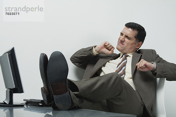 Geschäftsmann sitzend im Büro mit Füßen auf dem Schreibtisch