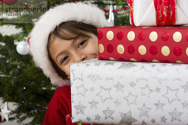 Junge schaut sich in einem Stapel von Weihnachtsgeschenken um.