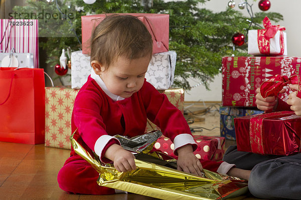Baby Mädchen beim Auspacken des Weihnachtsgeschenks