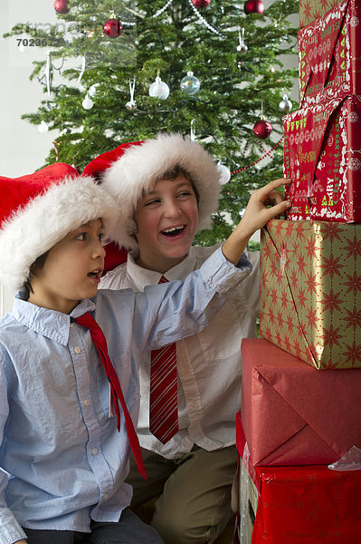Jungs schauen gespannt auf den Stapel Weihnachtsgeschenke