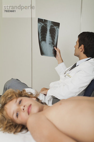 Arzt beim Röntgen  Junge nackt auf dem Untersuchungstisch liegend