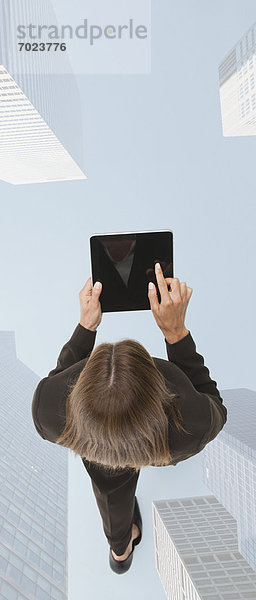 Geschäftsfrau mit digitalem Tablett beim Gehen auf überlagertem Bild von Wolkenkratzern
