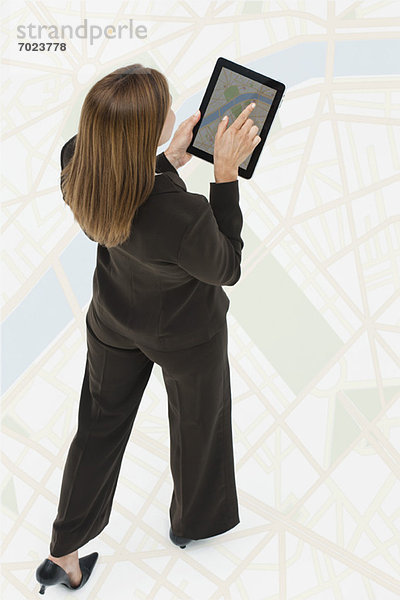 Frau betrachtet die Karte auf einem digitalen Tablett  während sie auf einer großen Karte läuft.
