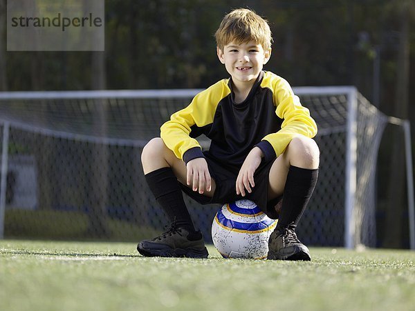 sitzend  Portrait  Junge - Person  Flachwinkelansicht  jung  Fußball  Ball Spielzeug