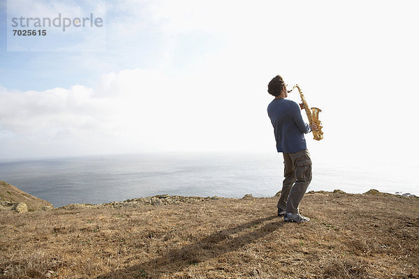 Mann Steilküste spielen Saxophon