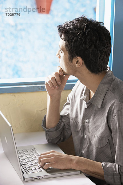 Mann mit Computer durch Fenster Suchen