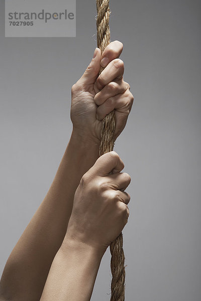 Woman climbing rope (close-up  focus on hands)