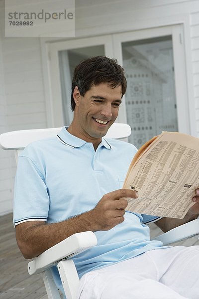 Mann  Stuhl  Mittelpunkt  Erwachsener  Zeitung  vorlesen