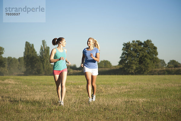 Zwei junge Frauen joggen auf einer Wiese