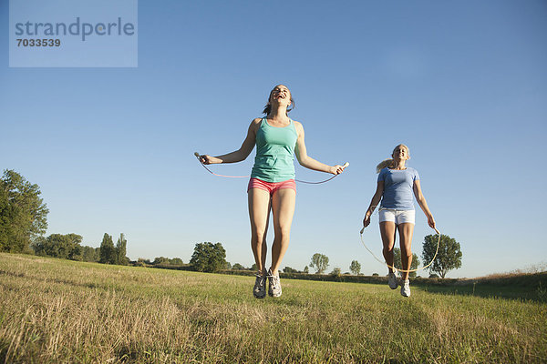 Zwei junge Frauen machen Seilspringen auf einer Wiese