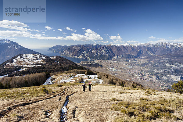 Wanderer beim Aufstieg zum Monte Stivo oberhalb vom St. Barbara  hinten der Gardasee mit dem Dorf Riva  unten das Dorf Arco  Trentino  Italien  Europa