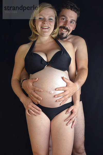 Werdende Eltern  Mann umarmt schwangere junge Frau mit Babybauch  9. Monat