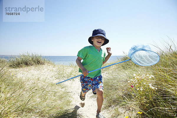 Junge mit Fischernetz am Strand