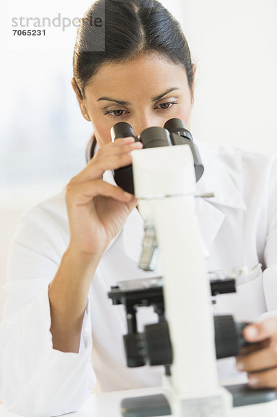 Weibliche Wissenschaftler auf der Suche durch Mikroskop