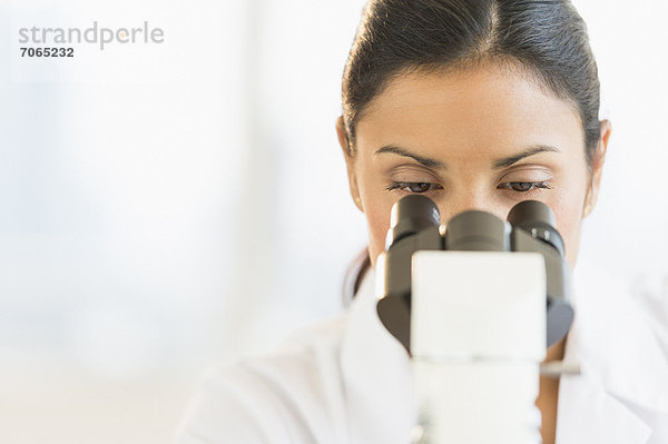 Weibliche Wissenschaftler auf der Suche durch Mikroskop