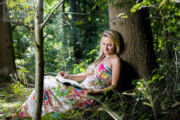 Junge Frau im Wald  beim Lesen