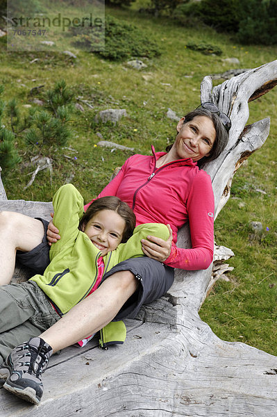 Wandererin  Bergsteigerin  Mutter rastet und relaxt mit ihrer Tochter auf einem Baumstamm  Raschötz bei St. Ulrich  Grödnertal  Südtirol  Alto Adige  Italien  Europa