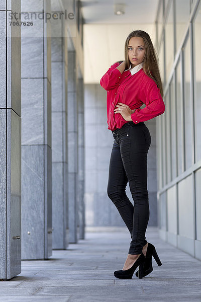 Junge Frau mit rotem Oberteil  schwarzen Jeans und hohen Schuhen