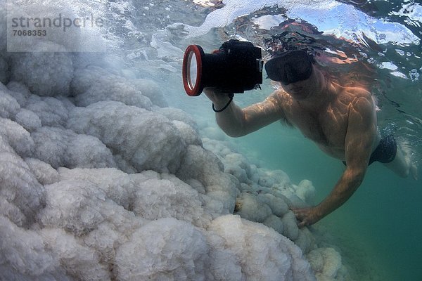 Mann fotografiert Salz-Formationen über Felsen im Toten Meer  Israel  Unterwasseraufnahme Unterwasseraufnahme