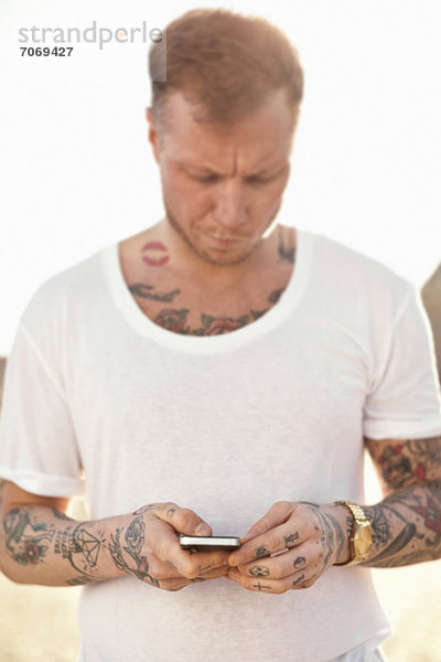 Tätowierter mittelgroßer Mann mit Textnachrichten im Freien