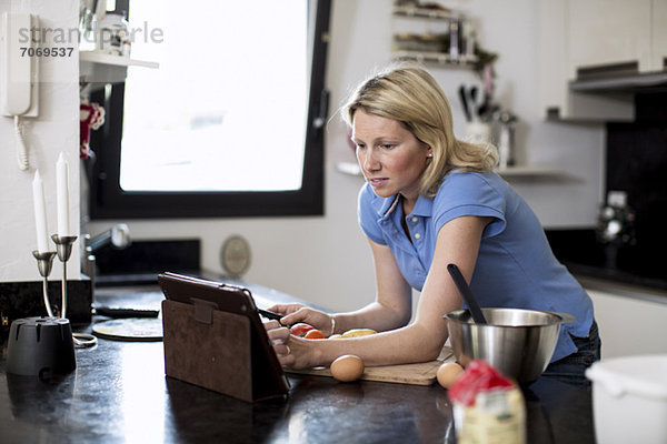 Frau sucht Rezepte in digitaler Tablette in der Küche