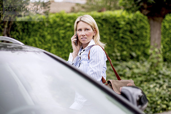 Mittlere erwachsene Frau  die mit dem Auto telefoniert.