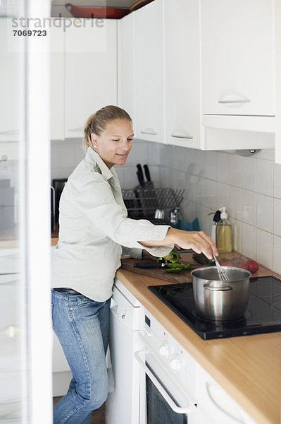Mittlere erwachsene Frau beim Kochen in der Küche