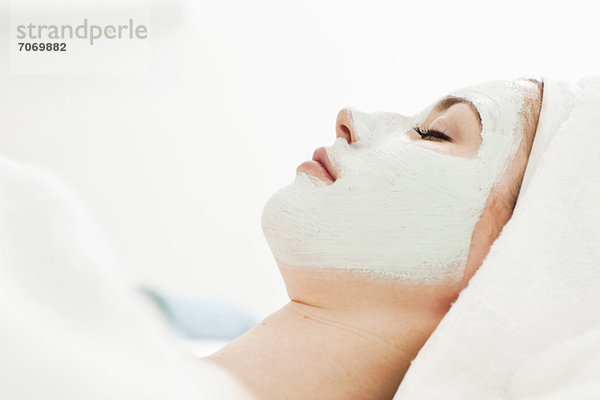 Seitenansicht einer jungen Frau beim Entspannen mit Gesichtsmaske im Beauty Spa