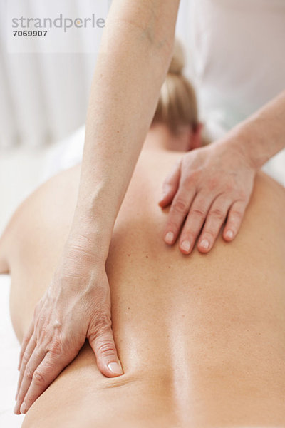 Reife Therapeutin mit Rückenmassage für erwachsene Frauen im Heilbad