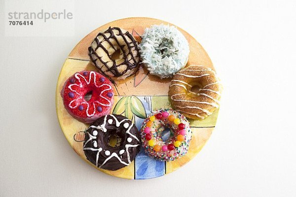 Gebackene Doughnuts mit verschiedenen Toppings auf einem bunten Teller