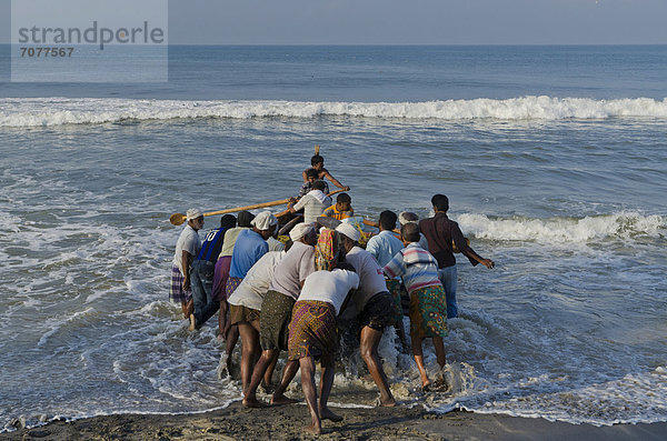 Fischer schieben ein Boot ins Meer  an der K¸ste in der Nähe von Varkala  Indien  Asien