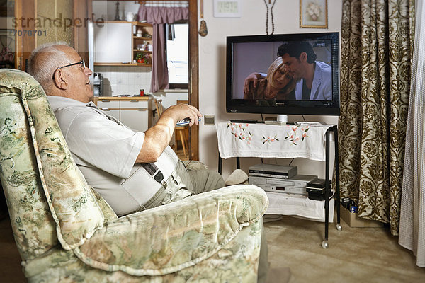 Älterer Mann vor dem Fernseher mit Fernbedienung