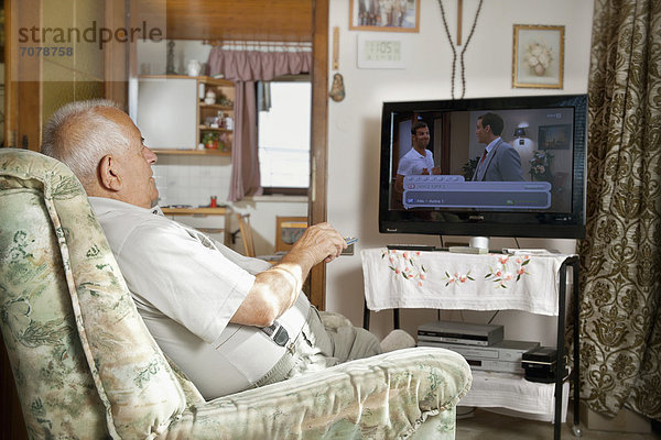Älterer Mann vor dem Fernseher mit Fernbedienung