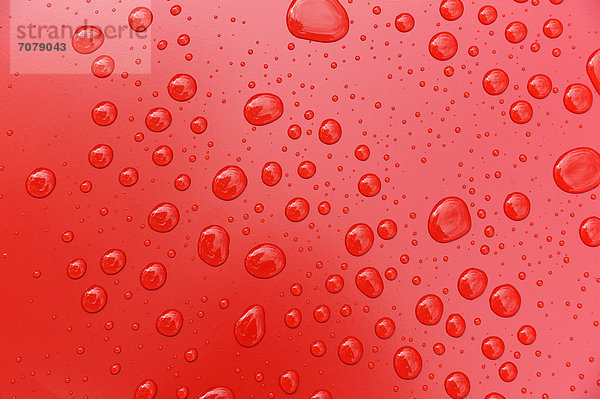 Wassertropfen auf einer roten Lackfläche