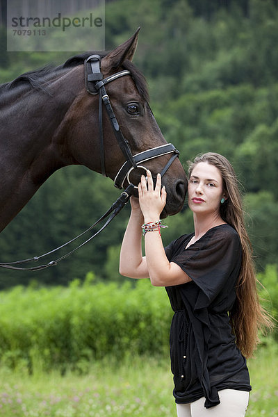 Junge Frau schmust mit Pferd  Hannoveraner  Brauner  Nordtirol  Österreich  Europa