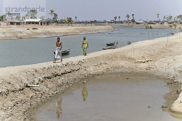 Ein Mann und eine Frau gehen ¸ber einen Damm  Zyklon Aila ¸berflutete den Ort 2009 schwer  Gabura  Sundabarns  Khulna District  Bangladesch  S¸dasien
