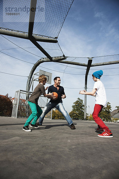 Vater und zwei Söhne spielen Basketball