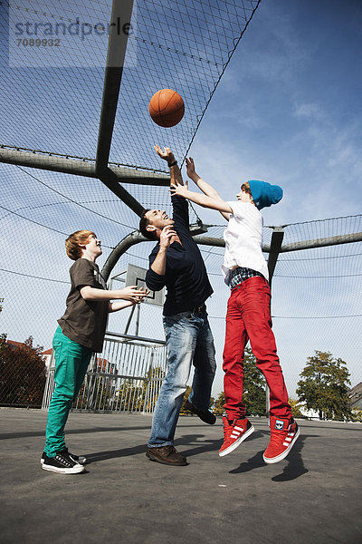 Vater und zwei Söhne spielen Basketball