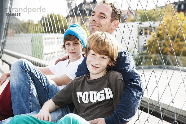 Vater und zwei Söhne auf einem Sportplatz