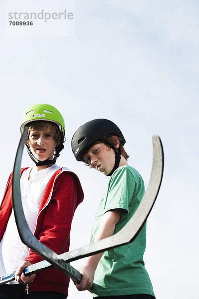 Zwei Jungen posieren mit Hockeyschlägern