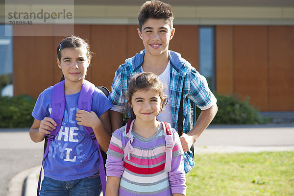 Drei lächelnde Kinder mit Schultaschen