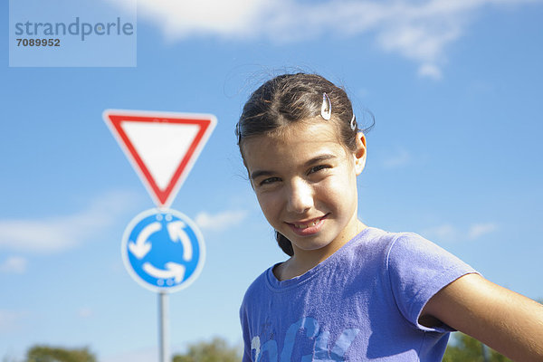 Lächelndes Mädchen steht vor einem Verkehrsschild  Portrait