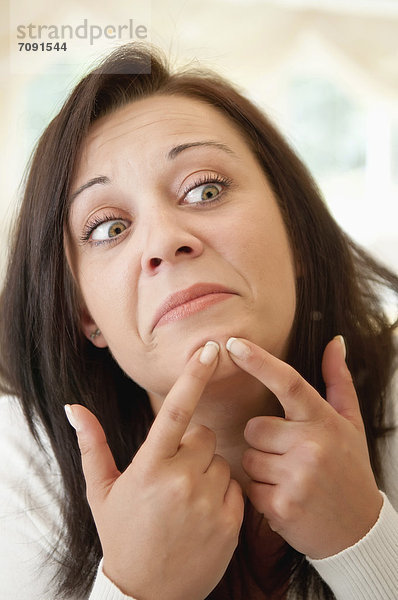 Young woman treating pimple  close up