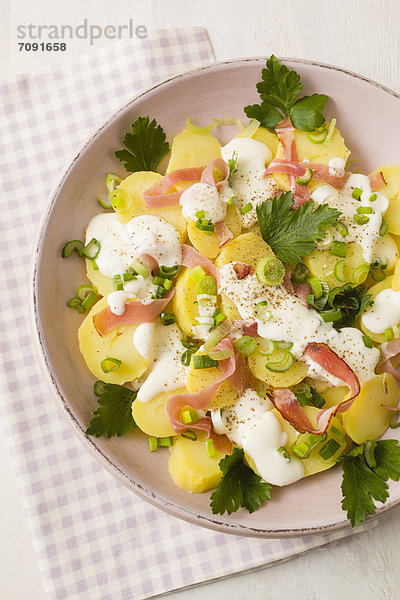 Potato salad garnished with spring onions  parsley and mayonnaise  close up