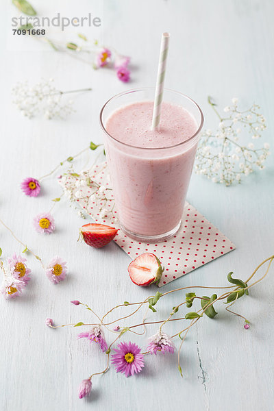 Glass of strawberry smoothie with cornflower blossom