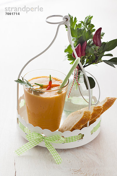 Glass of gazpacho with chillies  bread and parsley on tray