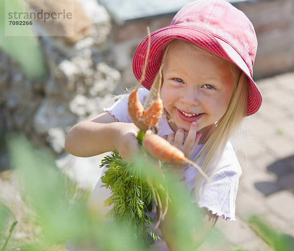Girl picking carrots in garden