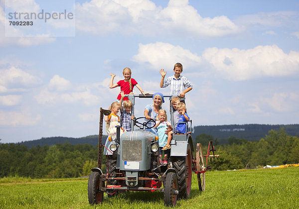 Frau mit Kindergruppe im alten Traktor sitzend