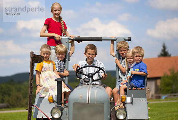 Germany  Bavaria  Group of children sitting in old tractor