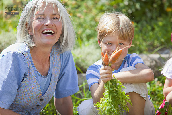 Reife Frau und Junge inspizieren Karotten im Garten